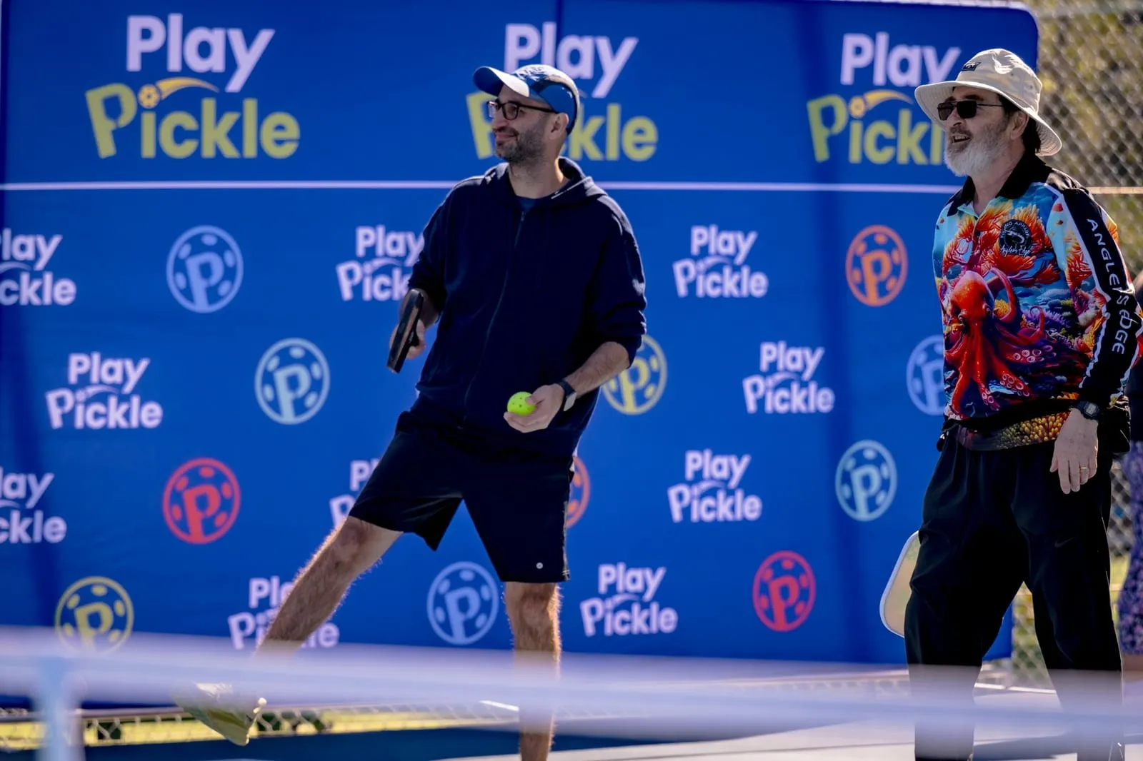 Players mid-game in front of a Play Pickle backdrop